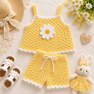 May include: A yellow crochet two-piece outfit consisting of a sleeveless top and shorts. The top features a large white daisy appliqué in the center and white scalloped trim along the edges. The shorts include a white drawstring waist.