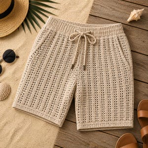 May include: Beige knit shorts featuring a vertical openwork pattern, an elasticized waistband, and a matching drawstring with metal aglets. The shorts are constructed from a textured, breathable yarn with a visible grid-like weave throughout.