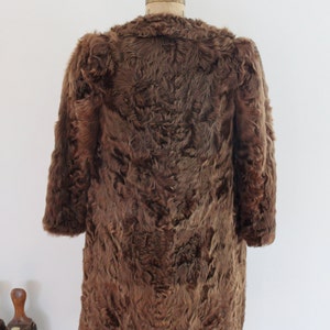 May include: A brown fur coat with a long, loose fit. The coat is made of a soft, fluffy fur and has a simple, classic design.