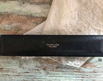 May include: A black rectangular box with gold lettering that reads "Tiffany & Co. New York".