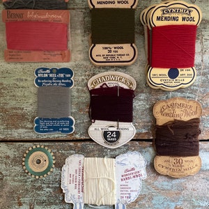 Puede incluir: Surtido de carretes de lana para zurcir vintage en varios colores, incluyendo rojo, marrón, verde y blanco. Los carretes están etiquetados con nombres de marca como "Republic", "Cynthia", "Chadwick's" y "Bernat".