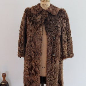 May include: A brown fur coat with a collar and button closures. The coat is on a dress form.