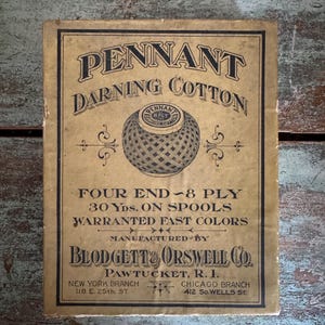 May include: A vintage box of Pennant Darning Cotton, featuring a spool of thread with a woven pattern. The box is brown with black text and states "Four End - 8 Ply 30 Yds. On Spools Warranted Fast Colors" and "Manufactured by Blodgett & Orswell Co. Pawtucket, R.I."