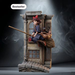 Peut inclure: Figurine détaillée d'une jeune sorcière en robe bleu foncé, nœud rouge et chaussures orange, chevauchant un balai. Un chat noir est assis dans un sac marron sur le balai. La scène se déroule devant une façade de bâtiment avec une étiquette "Bestseller".