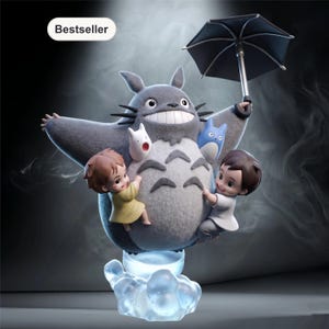 May include: A gray Totoro figure with an open umbrella, holding two small children and two smaller Totoro-like creatures. The figure is on a cloud-shaped base that emits a blue glow. The word "Bestseller" is in the top left corner.