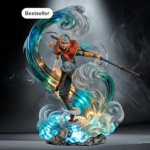 Op de afbeelding: Een beeldje van een personage uit Avatar: The Last Airbender, staand op een basis van waterachtige structuren. Het personage draagt een rode en gele outfit, met een staf in de hand. De waterbasis is blauw en groen, met een "Bestseller" label.