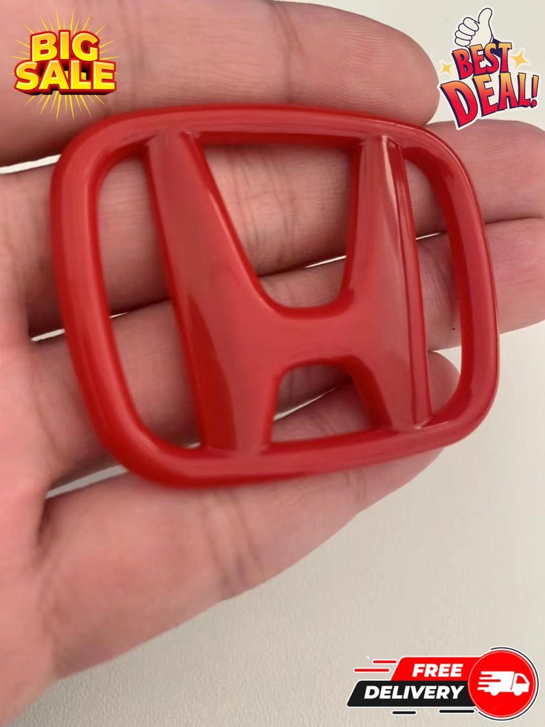 May include: A glossy red Honda emblem. The emblem is in the shape of a square with rounded corners and features the Honda logo in the center. The image also includes text that says "BIG SALE", "BEST DEAL!", and "FREE DELIVERY".