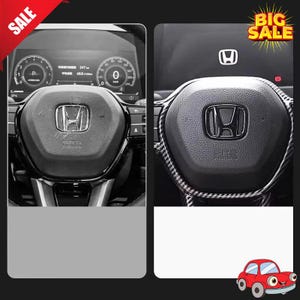 May include: Black steering wheel with the Honda logo in the center. The wheel has an SRS airbag label. The dashboard shows gauges and a digital display. A checkered pattern trim is visible on the steering wheel.