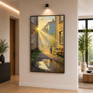 May include: A framed art print depicting a sunlit alleyway scene. The artwork features a young person holding a stick, standing near a bench and a puddle reflecting the buildings. The buildings are painted in warm, earthy tones, with bright sunlight streaming through.