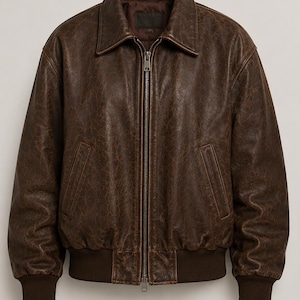 May include: A dark brown leather bomber jacket featuring a distressed texture, a classic point collar, and a full-length metal front zipper. The garment includes two slanted side pockets and ribbed knit cuffs and hem in a matching dark brown tone.