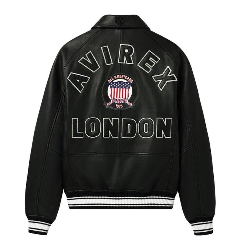 May include: Black leather jacket with white embroidered lettering that reads "AVIREX LONDON" on the back. A circular patch with an American flag design is centered between the words. The jacket has a ribbed collar, cuffs, and hem with white stripes.