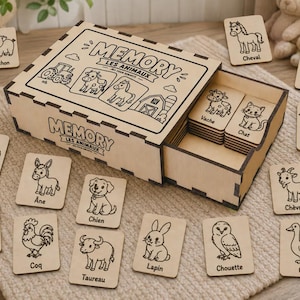 Peut inclure: Un jeu de mémoire en bois comprenant une boîte coulissante avec le texte MEMORY LES ANIMAUX et diverses illustrations d'animaux de ferme. Le jeu inclut plusieurs tuiles rectangulaires en bois, chacune gravée d'un dessin d'animal et son nom.