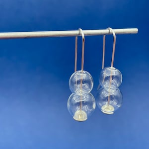 May include: A pair of silver dangle earrings with two clear glass spheres on each earring.