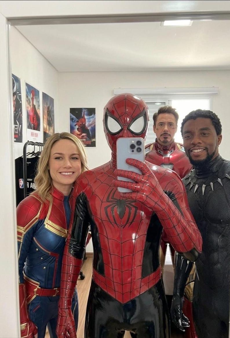 Puede incluir: Un grupo de cuatro personas con trajes de superh&eacute;roes, incluyendo un traje rojo y azul de Spider-Man, un traje rojo y azul de Captain Marvel, una armadura roja y dorada de Iron Man y un traje negro de Black Panther, posando para un selfie.