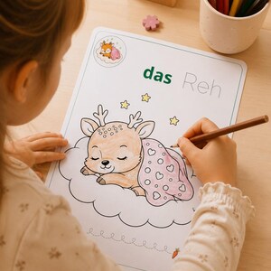 K&ouml;nnte beinhalten: Ein wei&szlig;es Ausmalblatt mit einem schlafenden Reh auf einer Wolke und dem Text das Reh. Das Reh ist in Braunt&ouml;nen ausgemalt und mit einer rosa Decke mit Herzmuster bedeckt. Gelbe Sterne umgeben das Reh und unten ist eine kleine Karotte abgebildet.