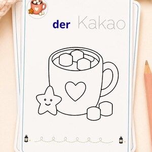 K&ouml;nnte beinhalten: Eine wei&szlig;e, rechteckige Lernkarte mit einer schwarzen Strichzeichnung einer Tasse voller Marshmallows, einem Herzsymbol und einem l&auml;chelnden sternf&ouml;rmigen Keks. Der Text lautet der Kakao, wobei der in Blau und Kakao in gepunkteter Schrift ist.