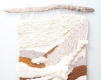 May include: A white, beige and brown woven wall hanging with a fringe border and white beads. The hanging is made with different textures and patterns of yarn.