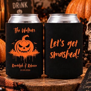 May include: Two black foam can coolers featuring orange graphics and text. One side displays a jack-o'-lantern with the text The Walkers, Randolph & Rebecca, and 10.30.2026. The other side features the orange text Let's get smashed! in a script font.