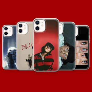 Puede incluir: Una colección de cinco fundas para iPhone con varios diseños. Las fundas presentan imágenes de una persona, ojos y texto. Las fundas están en fundas protectoras transparentes, con un fondo rojo.