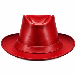 May include: A vibrant red fedora hat with a smooth, polished finish. The hat features a classic pinched crown design and a wide, structured brim with a stitched edge detail. The material has a subtle sheen, highlighting the deep red colour.