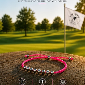 May include: A bright pink cord bracelet featuring seven metallic silver beads for counting golf shots. The bracelet has an adjustable sliding knot mechanism with two additional silver beads at the ends of the cord, designed for tracking strokes.