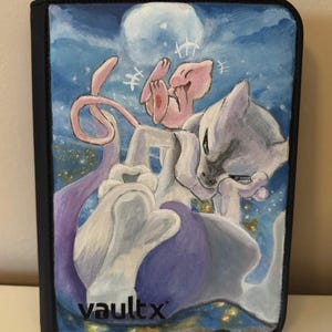 May include: A rectangular trading card binder with a black border and a front cover featuring a painted illustration of two creatures, one pink and one white and purple, against a blue night sky with a full moon. The text vaultx is printed in black.
