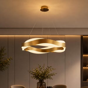 Peut inclure: Un lustre circulaire moderne de couleur dorée avec un design ondulé. Le luminaire est suspendu au plafond par de fins fils. Le lustre émet une lumière vive et chaleureuse de l'intérieur des bandes incurvées.