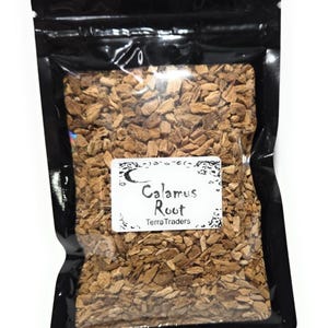 Può includere: Una busta di plastica nera richiudibile contenente piccoli pezzi essiccati di radice di calamo color marrone chiaro. Un'etichetta rettangolare bianca sul davanti presenta un grafico a mezzaluna e il testo: Calamus Root, Terra Traders.