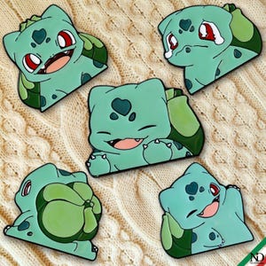 Op de afbeelding: Vijf emaille pins met het personage Bulbasaur in verschillende houdingen en uitdrukkingen. Elke pin is lichtgroen met donkergroene accenten, rode ogen en een bol op de rug. De pins tonen verschillende gezichtsuitdrukkingen, waaronder glimlachen, lachen en huilen.