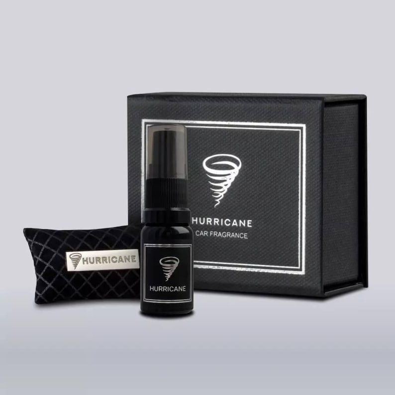 May include: A black car fragrance set with the word "HURRICANE" and a tornado graphic. The set includes a spray bottle, a small black pillow, and a black box with a silver border. The box also has the words "HURRICANE CAR FRAGRANCE".