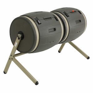 May include: A dual-chamber compost tumbler featuring two dark olive green cylindrical barrels mounted on a light tan metal frame. Each barrel includes a sliding door with black latches, a central rotating axis, and integrated handles for manual turning.