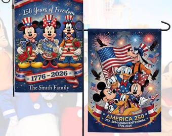 May include: Two garden flags featuring patriotic designs with Disney characters. One flag displays Mickey, Minnie, and Goofy holding letters spelling "USA" with the text "250 Years of Freedom" and "1776-2026". The other flag shows Disney characters with an American flag and the text "America 250".