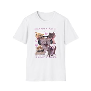 Può includere: T-shirt bianca con una grafica di cinque gatti con espressioni diverse. Un gatto indossa le cuffie e un altro gli occhiali da sole. Il testo "PROFESSIONAL YAPPER" è stampato sopra e sotto i gatti in viola.