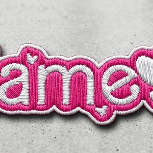 May include: A custom embroidered patch featuring the word Name in white thread with a thick hot pink border. The design includes small white butterfly motifs on the left and a larger white butterfly replacing the letter e at the end.