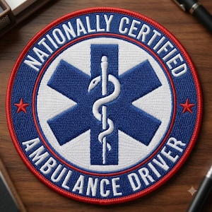 May include: A circular embroidered patch with a red border and a blue outer ring featuring the white text NATIONALLY CERTIFIED AMBULANCE DRIVER and two red stars. The center displays a white Star of Life symbol with a blue six-pointed star.