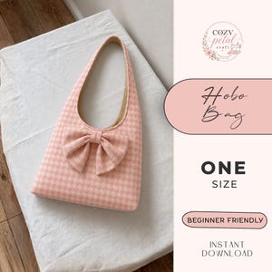 May include: A hobo bag featuring a pink and white houndstooth pattern with a large fabric bow on the front. The bag has a single shoulder strap and a light-colored interior lining. Text on the side reads: Cozy Petal Craft, Hobo Bag, One Size.