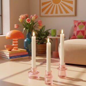 Pink taper candle holders displayed in a cosy sunlit living room with abstract wall art and Scandinavian boho decor styling.
