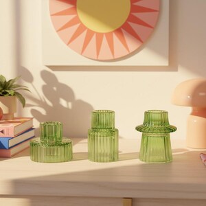 Green ribbed glass candle holders arranged on a cheerful dopamine decor shelf with colourful ceramics and warm natural sunlight.