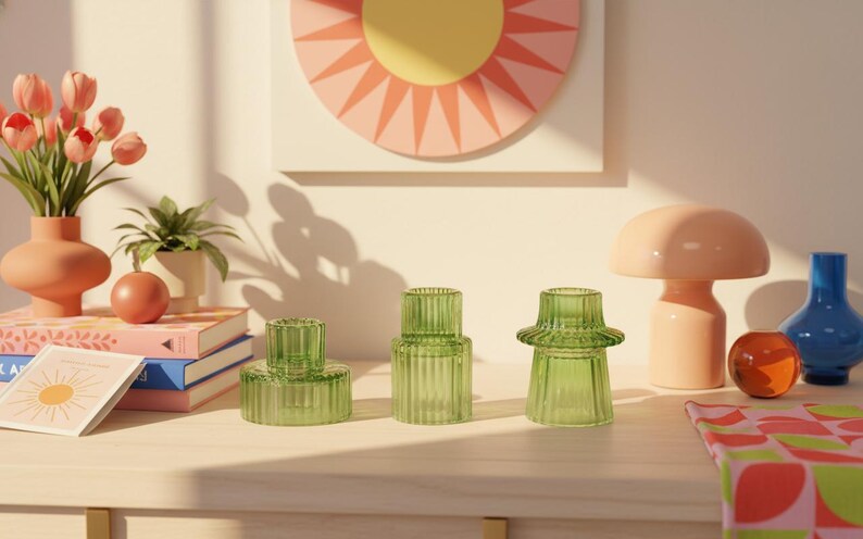 Green ribbed glass candle holders arranged on a cheerful dopamine decor shelf with colourful ceramics and warm natural sunlight.