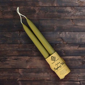 May include: Two olive green taper candles wrapped in brown paper with a label that reads "Authentic Bayberry Wax" and "Scent of the Bayberry Candle Company".