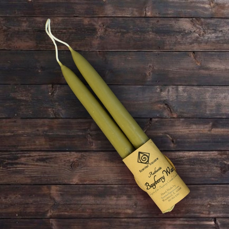 May include: Two olive green taper candles wrapped in brown paper with a label that reads "Authentic Bayberry Wax" and "Scent of the Bayberry Candle Company".