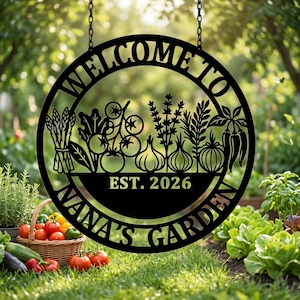 Könnte beinhalten: Ein rundes, schwarzes Metall-Hängeschild mit der Aufschrift WELCOME TO NANA'S GARDEN und EST. 2026. Das Design zeigt ausgeschnittene Silhouetten von Spargel, Tomaten am Strauch, Zwiebeln, Kräutern und Chilischoten innerhalb des runden Rahmens.