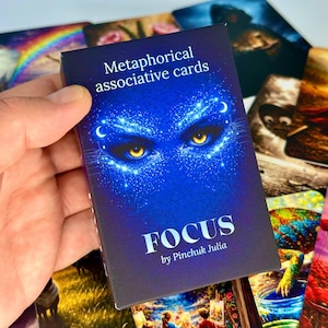 May include: A deck of "Metaphorical associative cards" with a blue cover featuring glowing yellow eyes and the word "FOCUS" in white. The deck is held in a hand, with other colourful cards visible in the background.