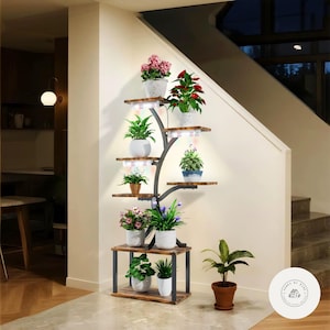 Puede incluir: Un estante para plantas de varios niveles con una estructura de metal negro y estantes de madera. El estante está lleno de varias plantas en macetas, incluyendo plantas con flores y vegetación. El estante tiene luces de cultivo LED incorporadas.