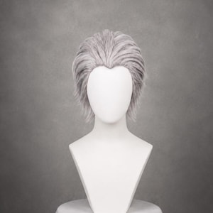 May include: A short, layered wig in a light silver-gray color, styled with a voluminous, swept-back appearance and a defined widow's peak at the hairline. The hair fibers are straight and textured, creating a structured look on a white mannequin head.