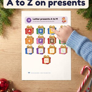 A child's hand matches letter C onto a present on the Letter presents A to M page
