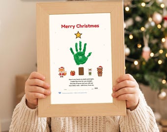Op de afbeelding: Een ingelijste kerst-handafdruk met een groene handafdruk in de vorm van een boom, bekroond met een gele ster. De print bevat illustraties van een vos, een cadeau, een beer en de tekst Merry Christmas en een gedicht.