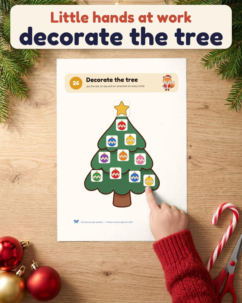 A child's hand presses an ornament onto the Decorate the tree page of the printable Christmas busy book