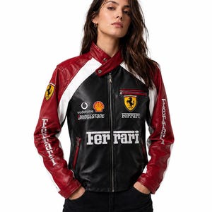 Może przedstawiać: Czarno-czerwono-biała skórzana kurtka wyścigowa z logo Ferrari na piersi i rękawach. Kurtka posiada logotypy sponsorów, takich jak Vodafone, Shell i Bridgestone, zamek błyskawiczny na całej długości oraz kołnierz zapinany na zatrzask.