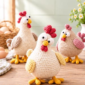 Peut inclure: Trois poules en crochet faites à la main avec des corps ronds, du fil texturé et des crêtes rouges proéminentes. Chaque poule présente de grands yeux blancs avec des pupilles noires, des becs jaunes et des pattes jaunes, en crème, brun clair et rose.